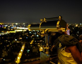 Femme avec son téléphone à la tour Eiffel de nuit
